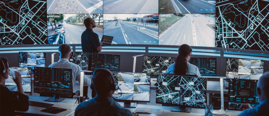 Security professionals monitoring city surveillance feeds on large 4K multiple input displays in a central command centre.